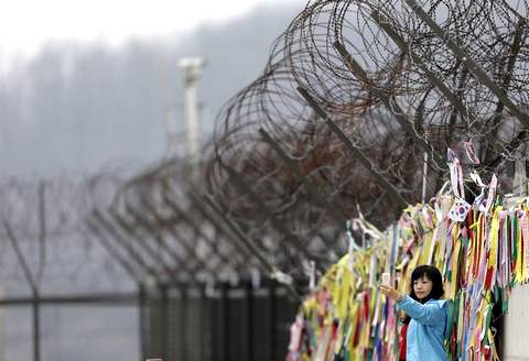 5 апреля 2013. Китайская туристка фотографируется на фоне демаркационной линии, разделяющей две Кореи. AP Photo/Lee Jin-man
