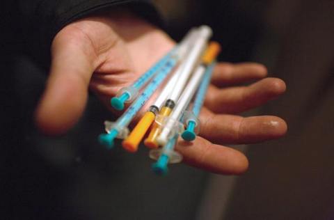 Наркоман показывает использованные шприцы в пункте обмена шприцов