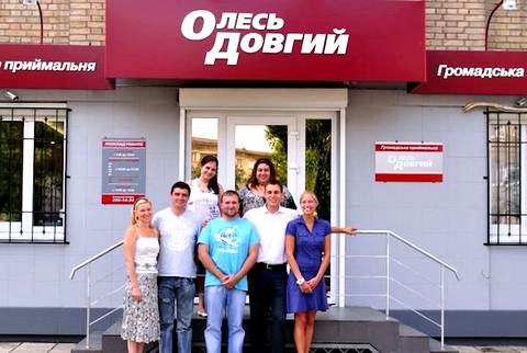 Олексій Новіков (нижній ряд, другий праворуч) та Марина Саакян (верхній ряд, праворуч) святкують відкриття приймальні Олеся Довгого