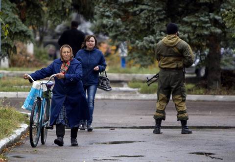 Residents walk past a pro-Russian rebel in the southern coastal town of Novoazovsk