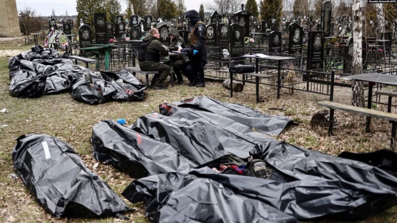 Поліцейські поруч із тілами загиблих під час російської окупації Бучі на місцевому кладовищі, квітень 2022 року