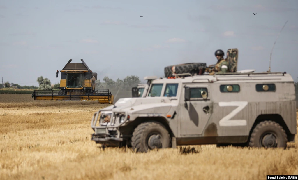 Військова машина Росії на українському полі під час збирання врожаю в нині окупованій частині Херсонської області, фото від 21 липня