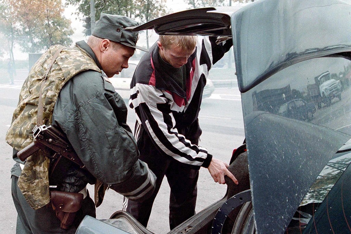 Сотрудник полиции заглядывает в багажник автомобиля по дороге в Санкт-Петербург, четверг, 16 сентября 1999 года, после очередного теракта в России. Фото: Анатолий Мальцев/EPA PHOTO/vk-hh