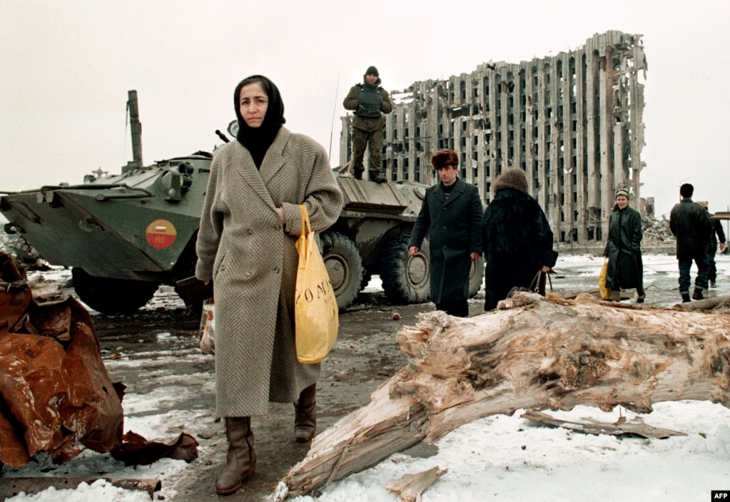 Жители Грозного проходят мимо танка российских федеральных войск и разрушенного здания президентского дворца Чечни. 1996 год