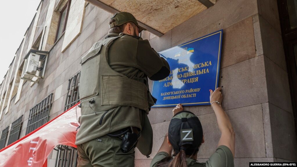 Російські військові змінюють табличку на міській раді окупованого українського Світлодарська. Травень 2022 року