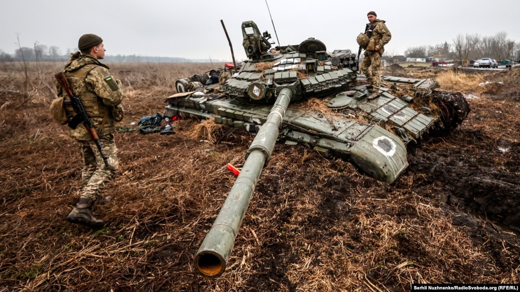Українські військовослужбовці оглядають російський танк у селі Нова Басань на Чернігівщині після відновлення контролю над цим населеним пунктом, 1 квітня 2022 року