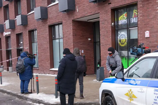 Мащина полиции возде входа в подъезд в жилой дом, фотографы и просто прохожие
