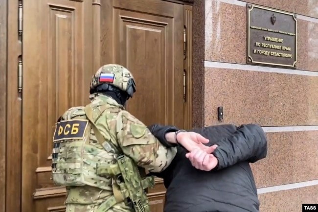 Співробітник ФСБ супроводжує затриманого до будівлі управління ФСБ в анексованому Криму, грудень 2022 року