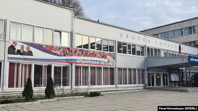 Банер на фасаді Палацу піонерів у Сімферополі, присвячений російській анексії Криму. Березень 2026 року
