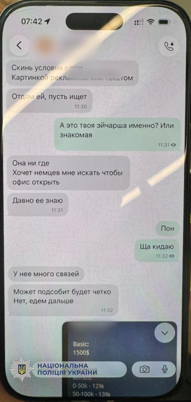 Фотографія екрана смартфона з відкритим діалогом у месенджері, де ведеться листування російською мовою. Ліворуч відображаються сірі хмаринки вхідних повідомлень із текстом про умови роботи картинкою чи текстом, пошук людей для відкриття офісу та наявність зв'язків. Праворуч розташовані зелені хмаринки вихідних повідомлень із текстом запитання про ейчаршу та відповідями Пон і Ща кидаю. У нижній частині чату прикріплено зображення з англомовним текстом, де видно слова Basic 1500 доларів та цифри відсотків. У верхньому лівому кутку екрана смартфона вказано час 07:42. У лівому нижньому кутку поверх зображення накладено офіційний логотип Національної поліції України з синьо-жовтим гербом-тризубом та написом Національна поліція України.