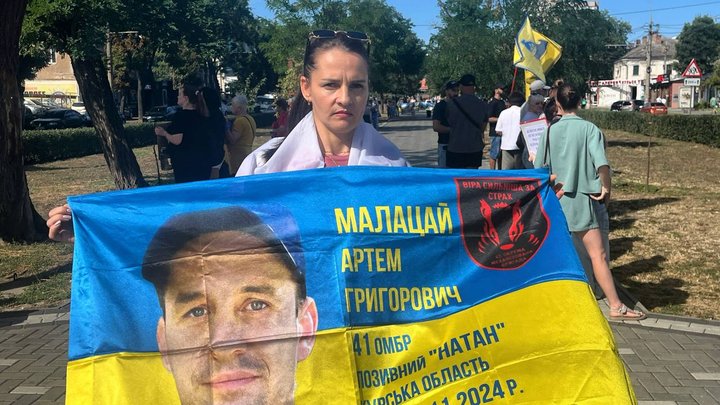 Аліна тримає прапор із портретом свого безвісти зниклого чоловіка. Фото з особистого архіву Аліни