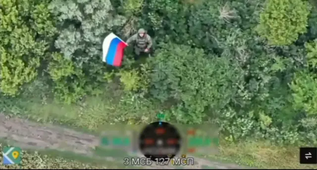 Російський військовий розмахує прапором в кущах
