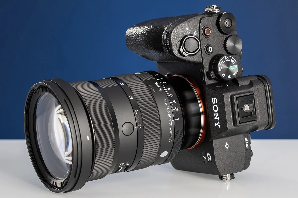 Студійне фото об'єктива Sigma 24-70mm f/2.8 DG DN II Art на камері Sony A7 IV з ракурсу зверху, де видно розмітку діафрагми, шкалу фокусних відстаней та верхню кнопку AFL
