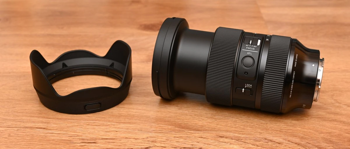 Попереднє покоління об'єктива Sigma 24-70mm f/2.8 DG DN Art Gen 1 з висунутим тубусом поруч із блендою на дерев'яному столі