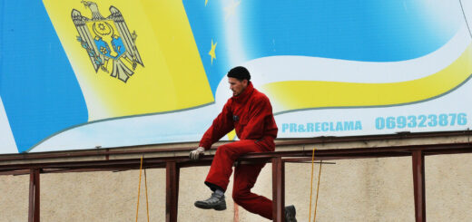 рабочий ремонтирует рекламный билборд с поблекшими на солнце флагами Молдовы и Гагаузии в Комрате. Фото: Daniel Mihailescu /AFP / East News