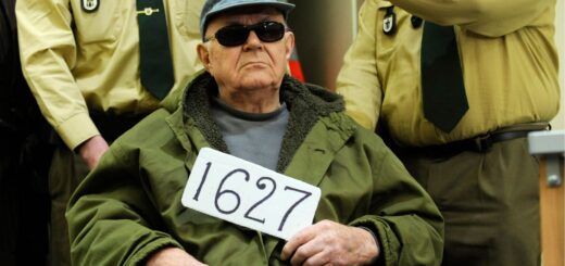 Джон Демьянюк держит табличку 1627 (номер советского следственного досье), в то время как его ввозят в зал суда в Мюнхене, Германия, 22 февраля 2011 года Фото: AP/Lukas Barth
